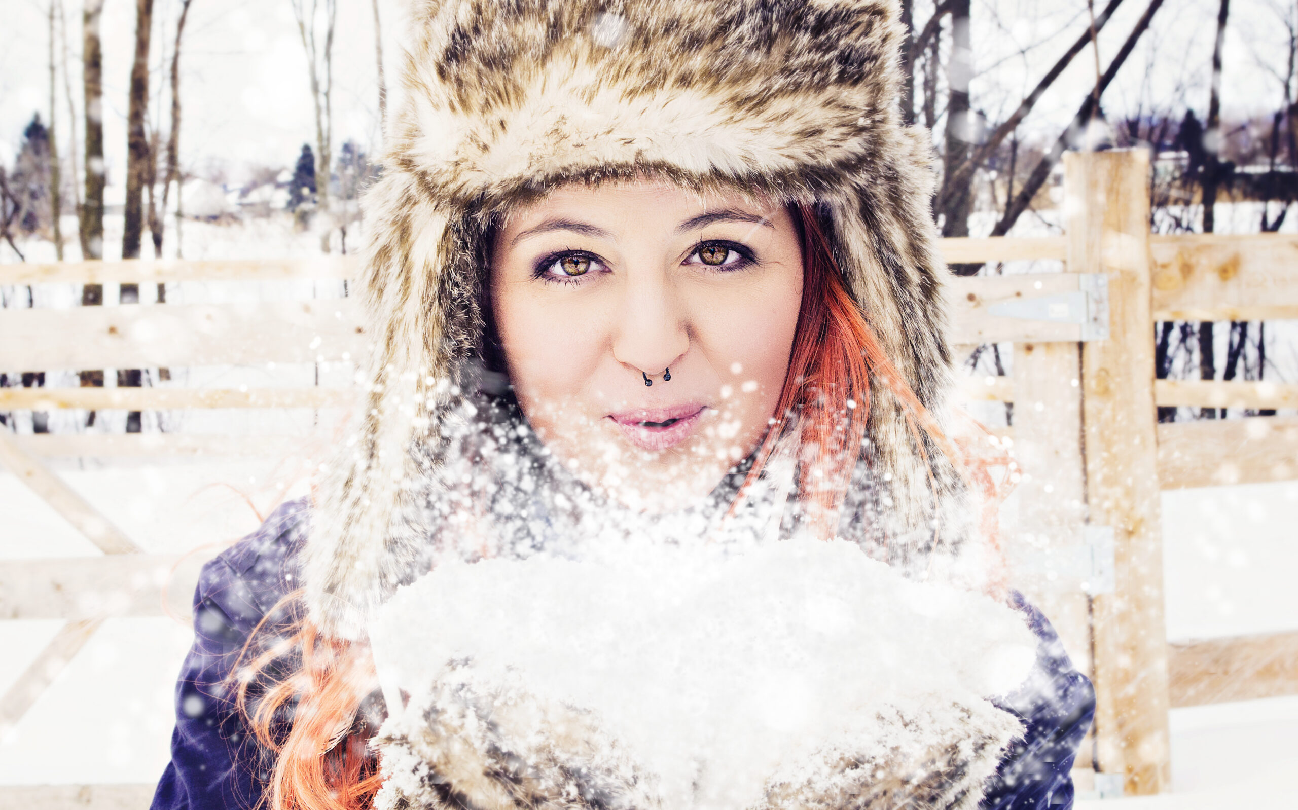 Photo d'une femme au cheveux roux soufflant sur la neige.
