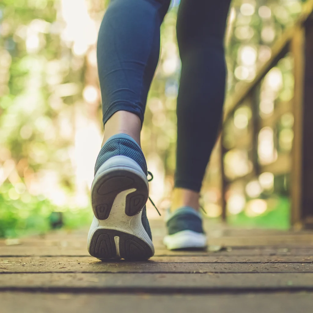 Personne marchant sur un sentier en forêt, illustrant l'idée des 10 000 pas comme objectif de santé.